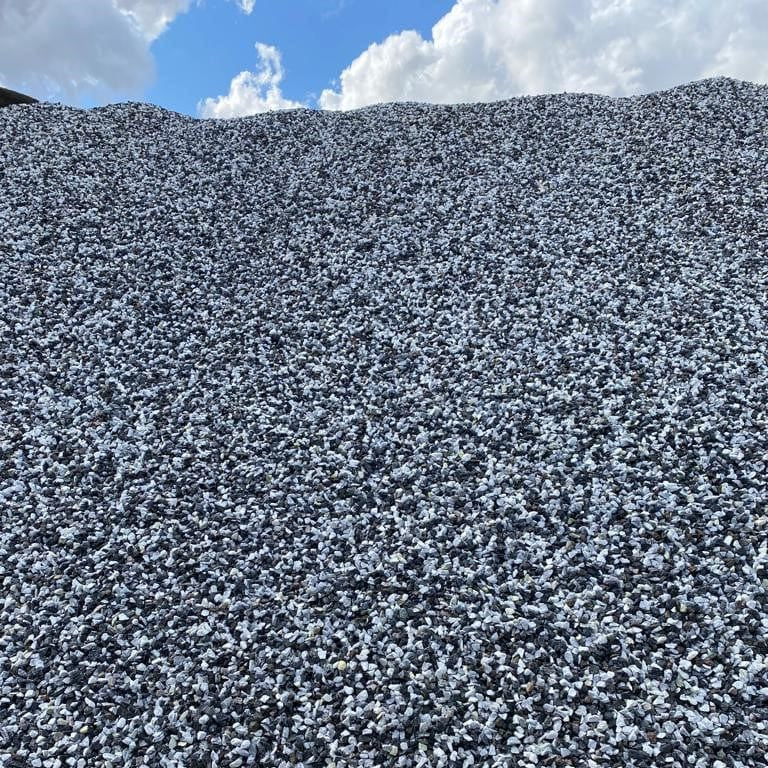Large pile of small stones or gravel under a blue sky with clouds
